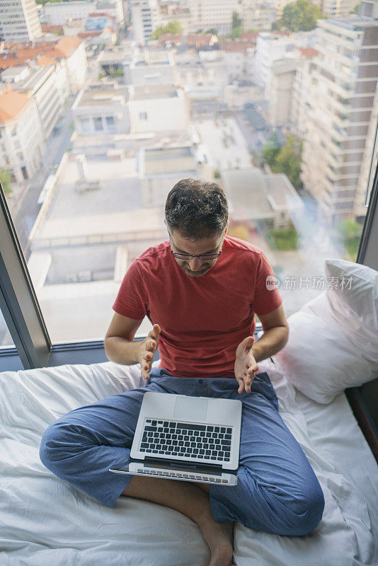 男人在家工作，用笔记本电脑开会视频聊天