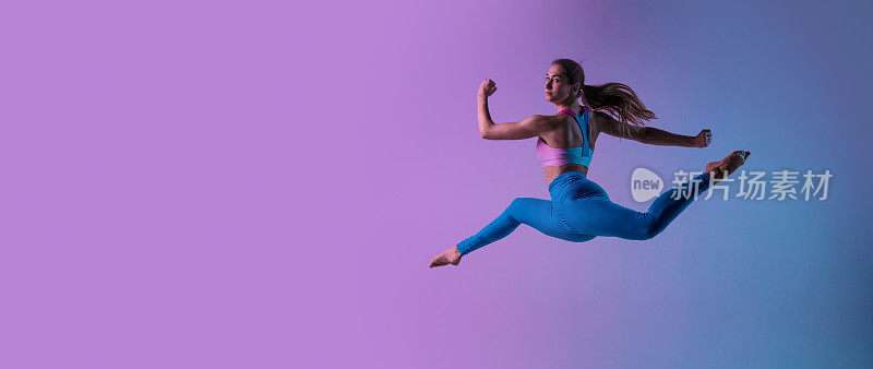 年轻的运动妇女训练孤立在霓虹灯梯度演播室背景。运动和优雅的