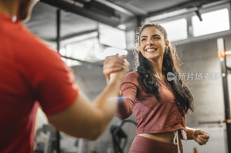 年轻的女人和男人在体育馆的高强度训练后正在握手