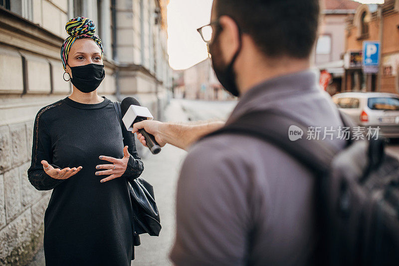 一名男性新闻记者在街上采访一名女性