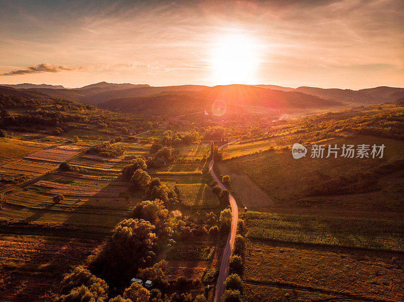 鸟瞰图的乡村景观与蜿蜒的道路和日落