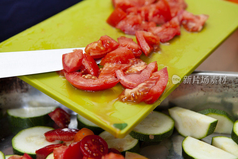 用刀将切好的番茄从砧板上切下来，放入不锈钢锅中