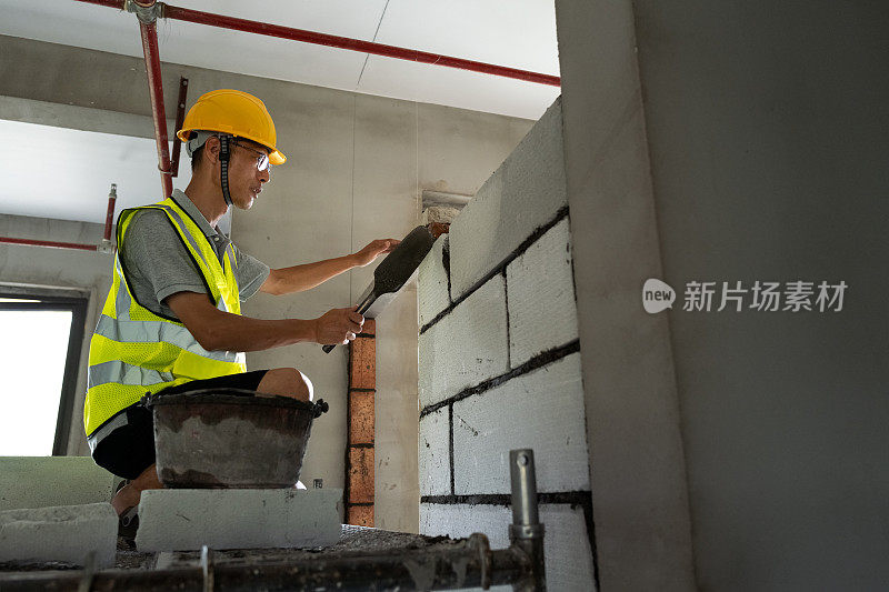 亚洲中年男性抹灰工作在建筑工地