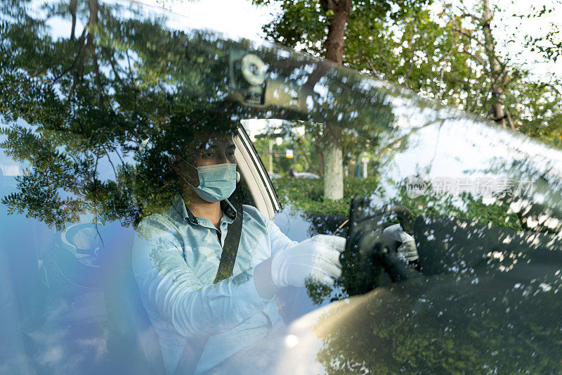 一名男性司机戴着呼吸面罩透过汽车玻璃看