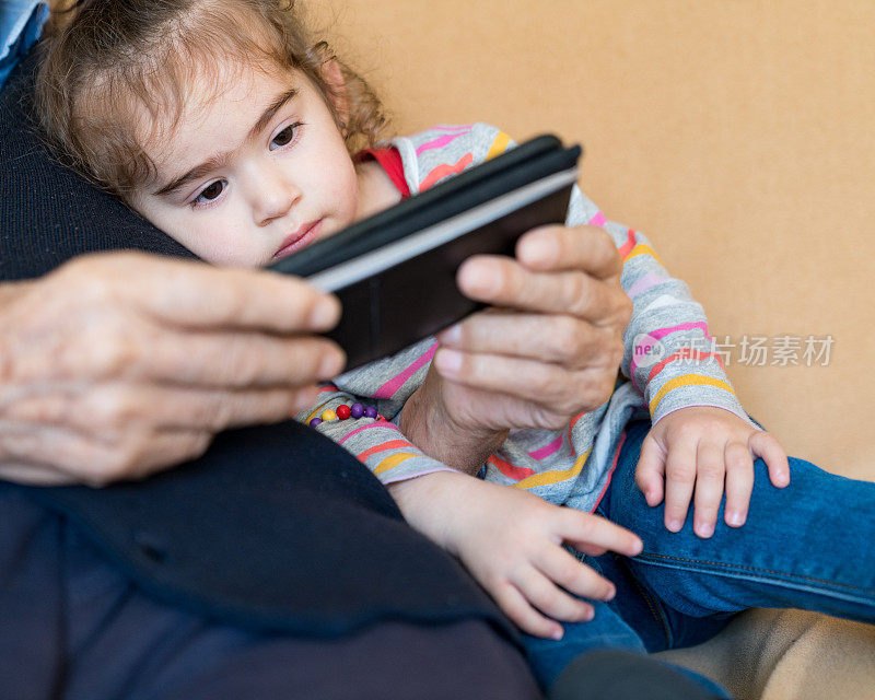 爷爷和孙女坐在沙发上使用智能手机