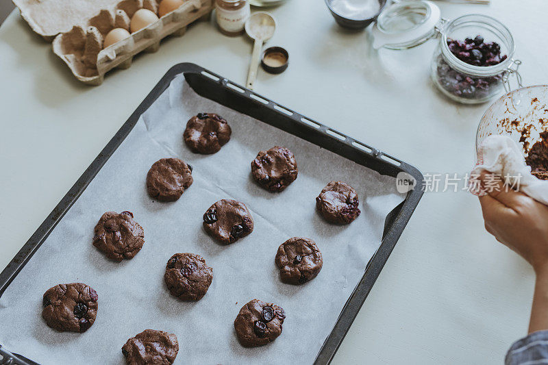 在家里烘焙:一个匿名的女人塑造巧克力曲奇并把它们放在烤盘上