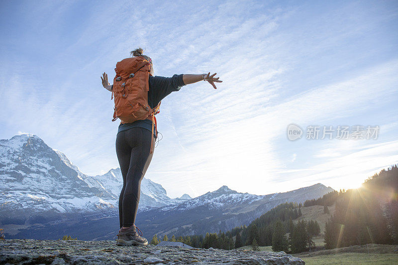 日出时分，女徒步旅行者在山脊上休息