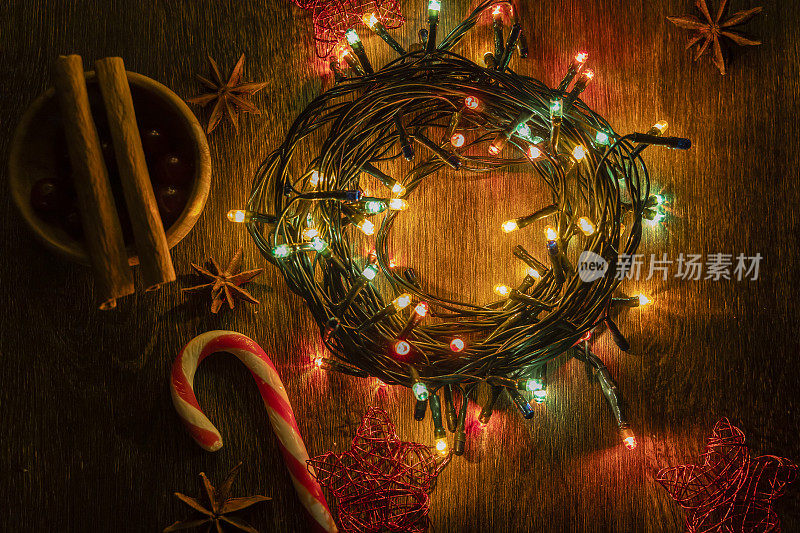 圣诞彩灯在一棵老树上滚成一个圈，用八角和肉桂装饰。柺杖糖