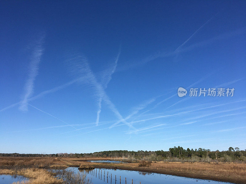 在被水淹没的农田上，蓝色天空中纵横交错的尾迹