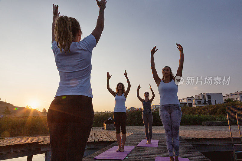 日出时分，一群妇女在城市的码头上练习瑜伽