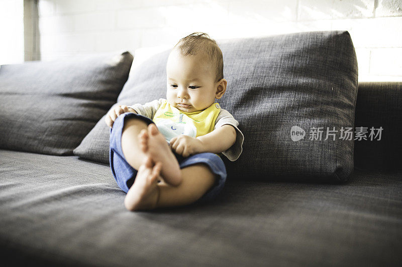 亚洲婴儿独自坐在沙发床上