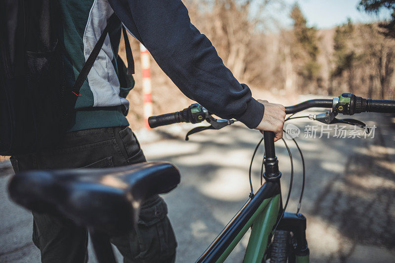 一个骑公路自行车的男性骑在一条被森林包围的山路上。这是一个美丽的冬日阳光灿烂的日子，年轻人可以在大自然中骑行。健康的生活方式。