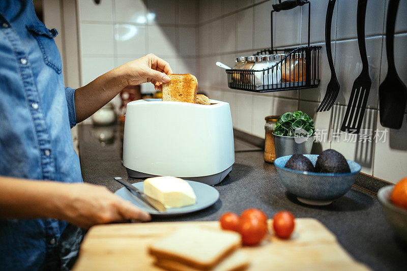 一个面目全非的女人用烤面包机为早餐准备三明治