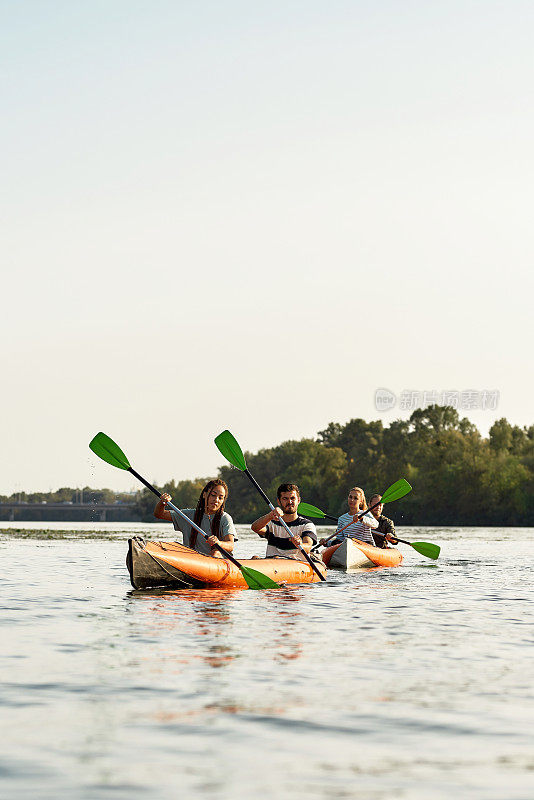 年轻的朋友们一起在河上划船，在夏天的一天在户外度过周末