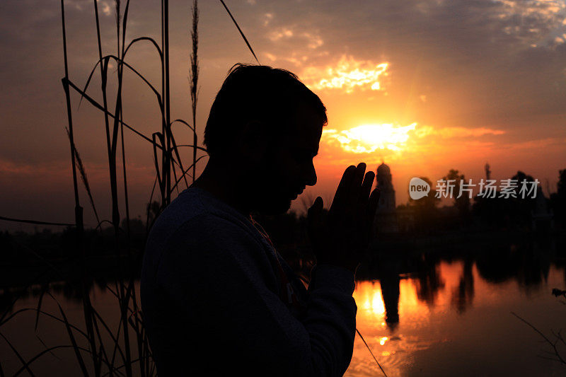 年轻男子向上帝祈祷的剪影