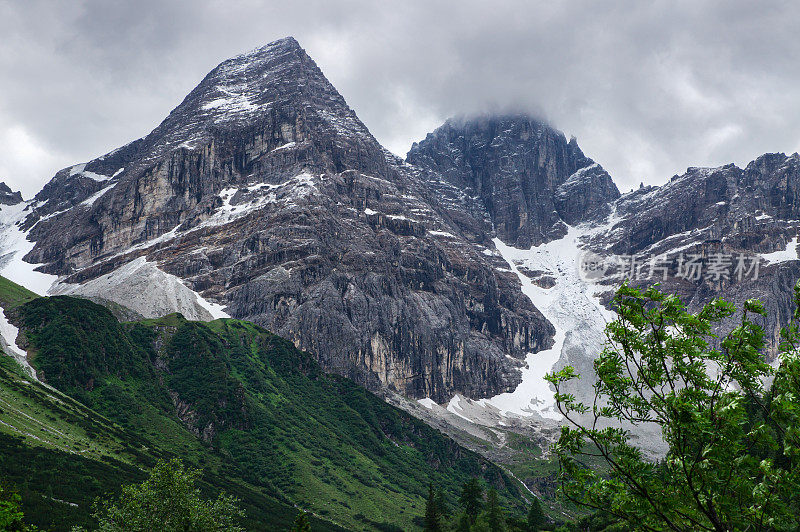 一座雄伟的山峰从阿尔卑斯山的绿色中巍然耸立。