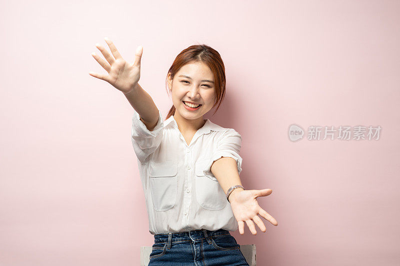 抓住这个机会。乐观活泼可爱的亚洲金发女孩伸出手向前伸展手臂相机拥抱拥抱想抱可取的产品微笑逗乐快乐粉红色背景。