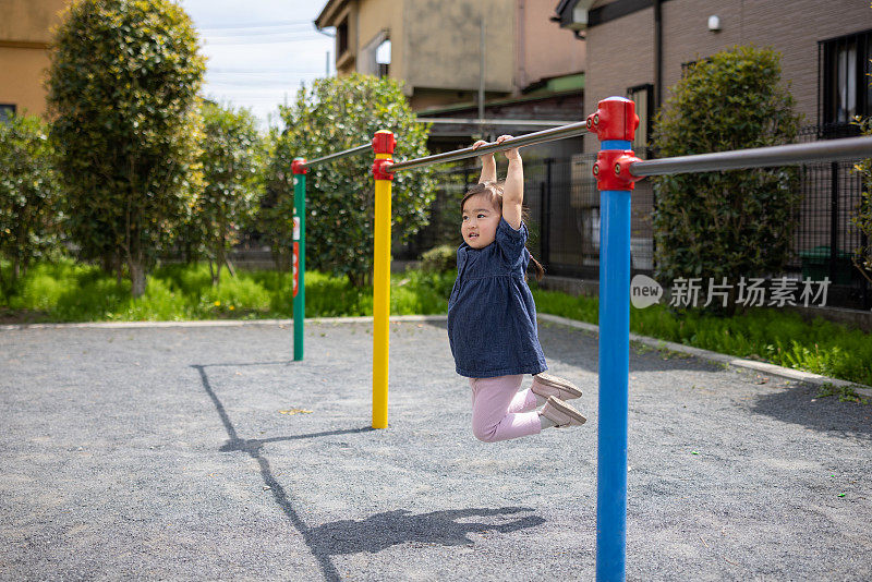 小女孩在公园里玩单杠