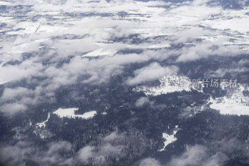 从飞机窗口透过白云看到的雪景。在冬天旅行。
