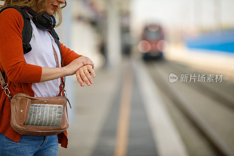 复制空间拍摄的女人在等待火车出发时查看时间