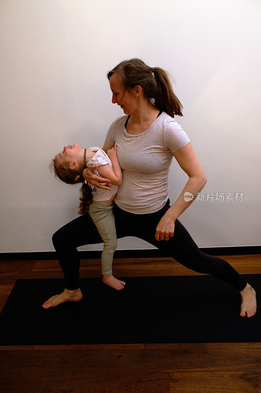 妈妈和婴儿瑜伽-肖像的母亲和女儿练习瑜伽一起在瑜伽垫上