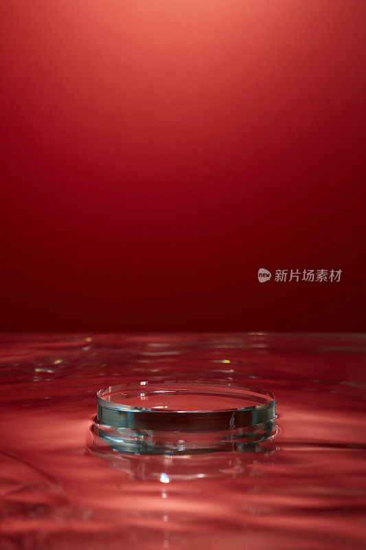 红色与水的背景配合透明的裙台装饰，留白空间为产品展台广告，内容抽象