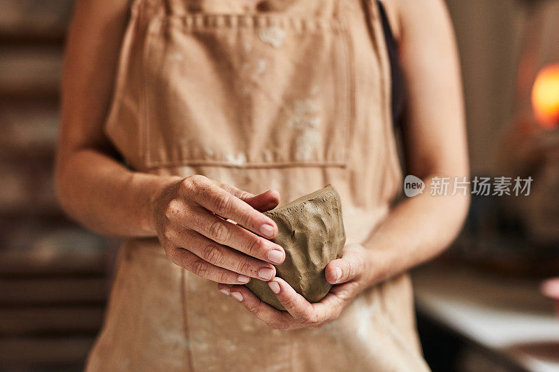 妇女手拿粘土工作的特写。陶器作坊里的女性，手掌上有圆边模具。在工作室里，专业的工匠用质感手工制作了一件艺术品。