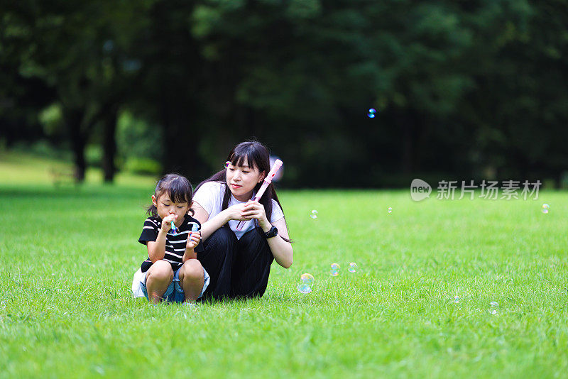 妈妈和女儿在公园里玩肥皂泡