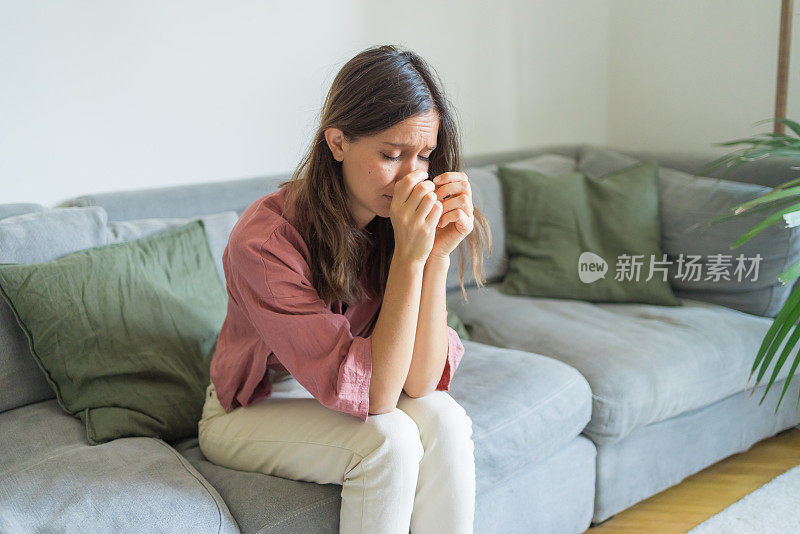 悲伤的年轻女子坐在客厅的沙发上