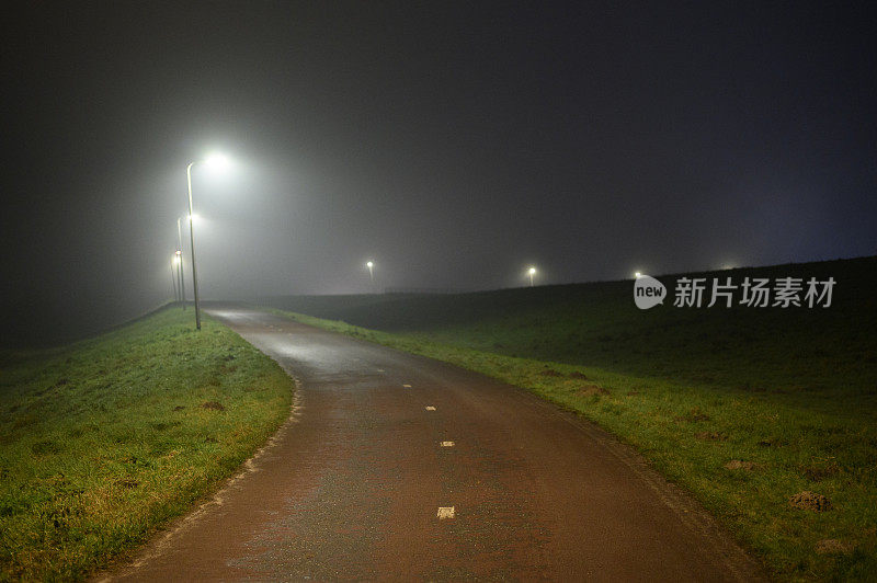 雾蒙蒙的夜晚，路灯照亮了这条小路