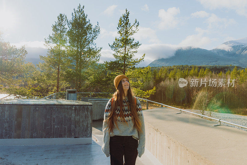 在挪威隆丹国家公园，背着双肩包的微笑女子凝视着山上的风景