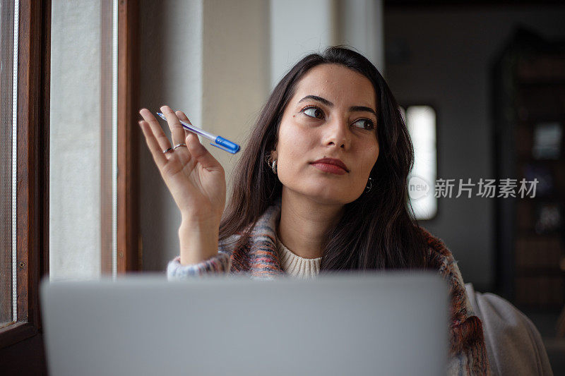 年轻的黑发女子坐在公共图书馆若有所思。