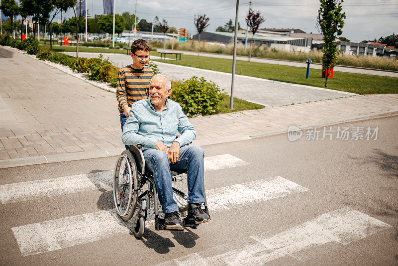 小孩在轮椅上照顾过马路的爷爷奶奶