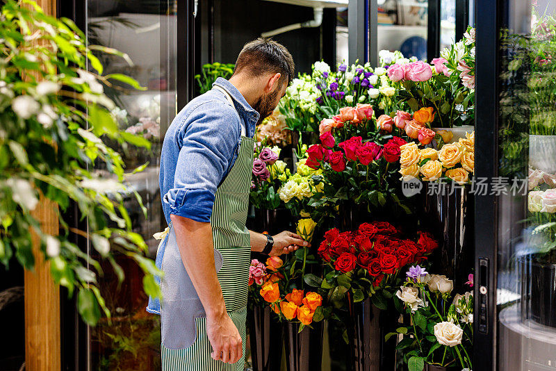 一位男性花店老板正在冰箱里摆放鲜花。