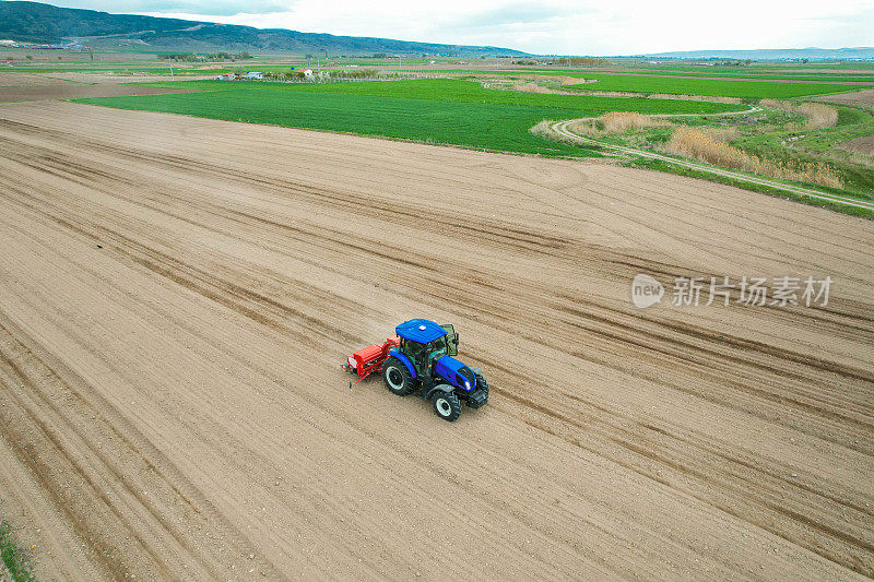 无人机俯视图的农民种植玉米与拖拉机和播种机的田地