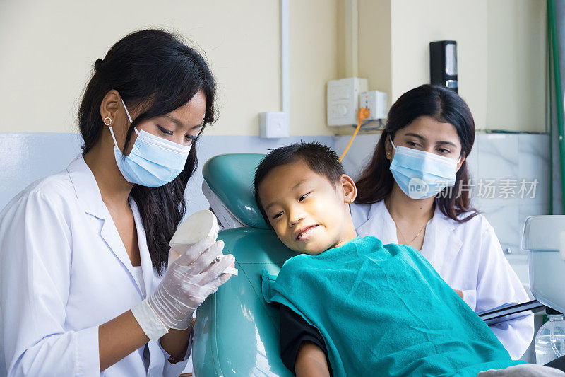 快乐的孩子在牙医诊所与女护士和医生