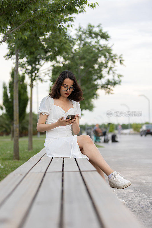 年轻女子正坐在公园的长椅上。