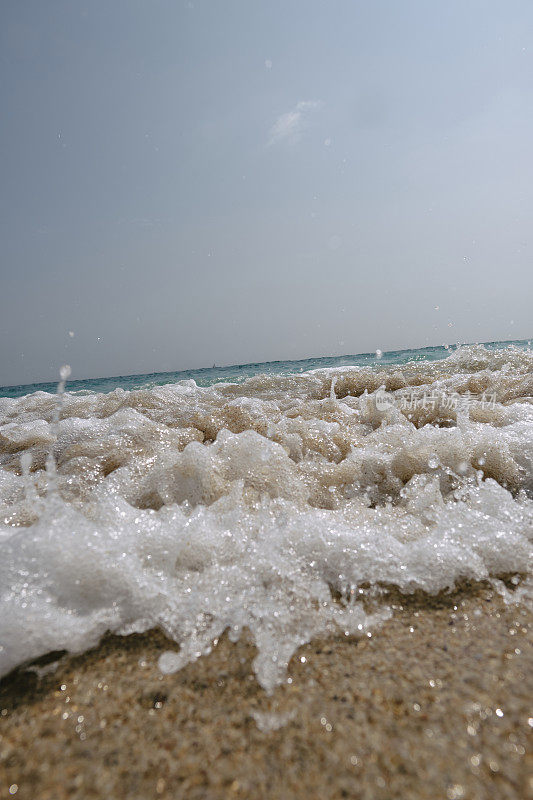 6月的一个晴朗的日子里，康沃尔郡佩顿温德海滩的海岸线上，一波海浪冲进相机的特写。