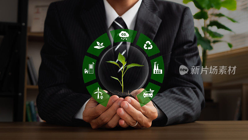 商人手持印有绿色企业ESG、二氧化碳和净零标志的工厂。可持续发展的概念，可持续发展目标，绿色技术，世界地球日和环境技术。