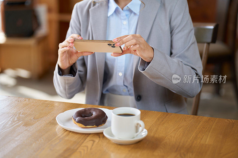 一名亚洲女子在咖啡馆用智能手机拍照