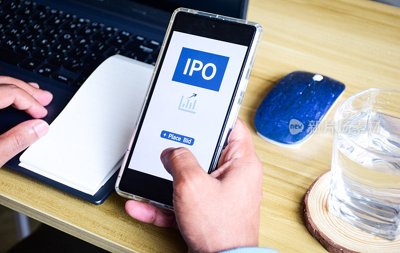 一名男子在他的智能手机上为IPO(首次公开募股)投资投标。企业财务理念。