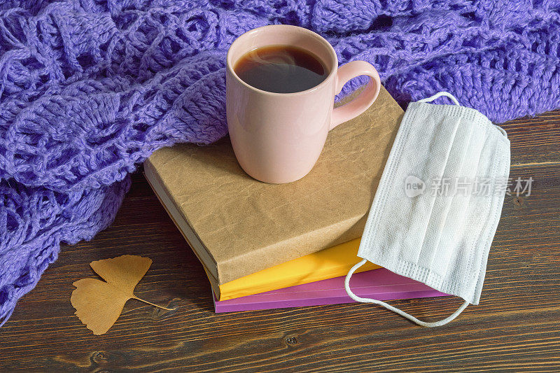 秋天。质朴的桌子上放着书、暖和的围巾、一杯咖啡和面罩