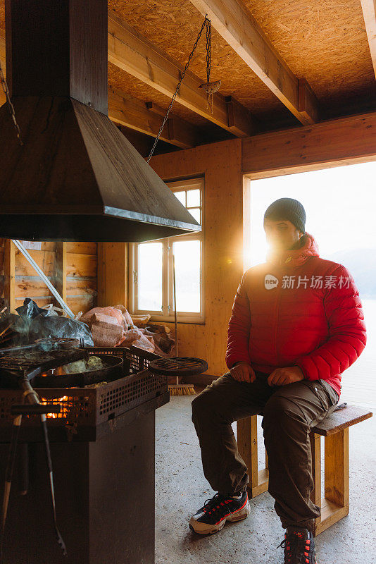 挪威峡湾，一名男子在炉火旁取暖