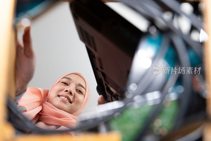 电子废物管理。美丽的亚洲穆斯林妇女把电子垃圾放在纸板箱里，送去回收或妥善处理。环境可持续性。电子垃圾。
