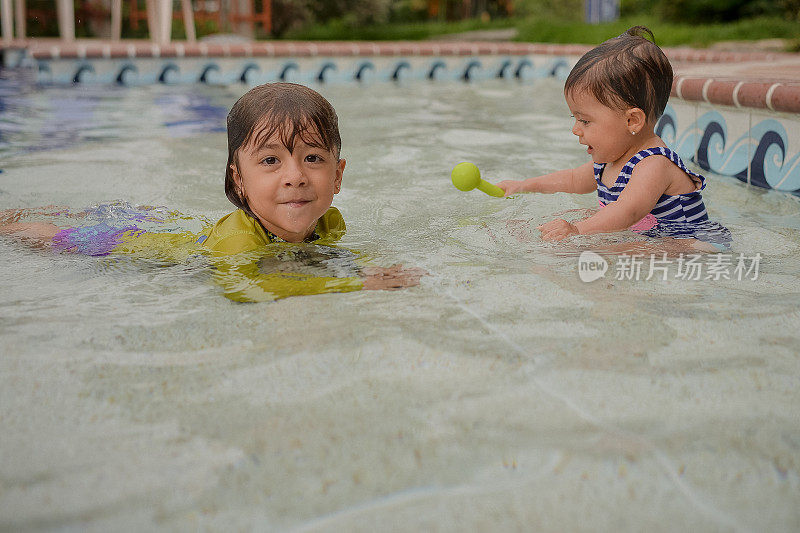 两个女孩或姐妹在游泳池里游泳和玩耍