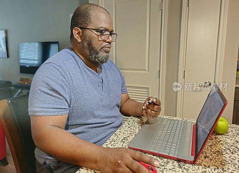 老年男性在家用笔记本电脑，手里拿着银行借记卡