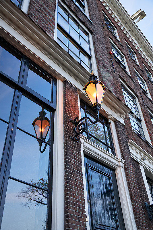 阿姆斯特丹历史悠久的运河房屋立面和黄昏时的街灯