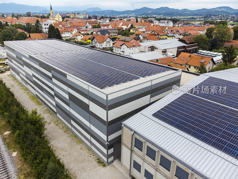 以老城区为背景的仓库屋顶上的太阳能电池板鸟瞰图，展示了城市环境中的可再生能源。地点:斯洛文尼亚的扎莱克