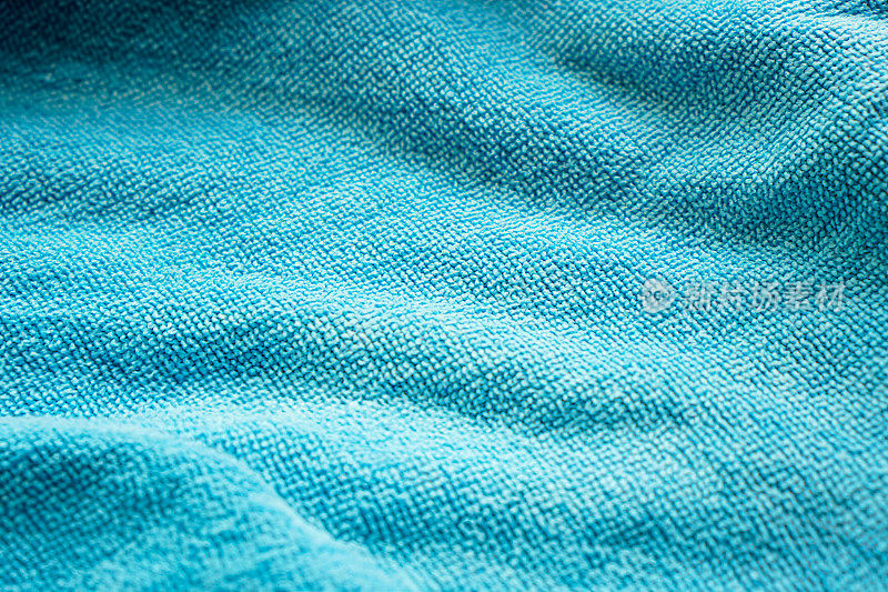 蓝色图案的棉布毛巾的特写，折叠起来，美丽地反射着太阳的光线。