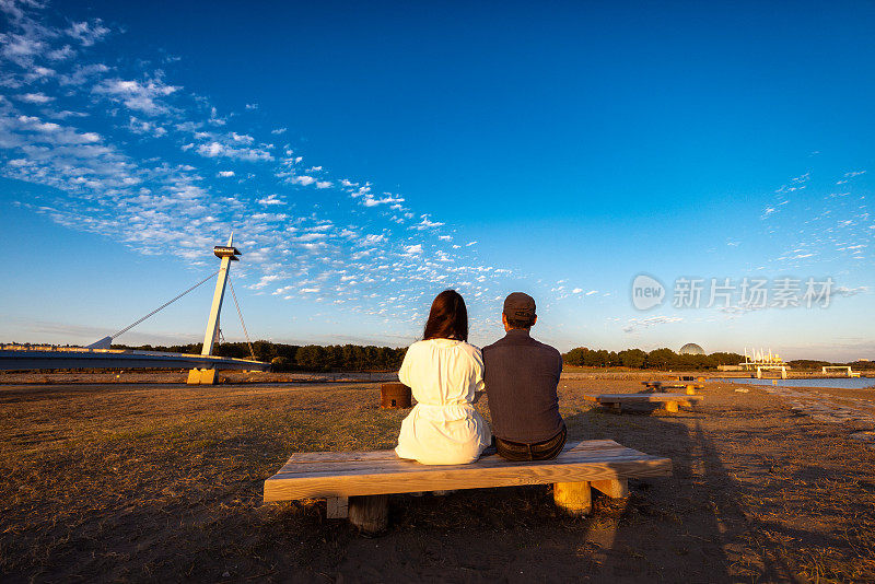 一对夫妇在日落时分坐在长凳上